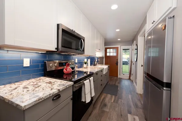 a kitchen with stainless steel appliances granite countertop a stove refrigerator and a microwave oven