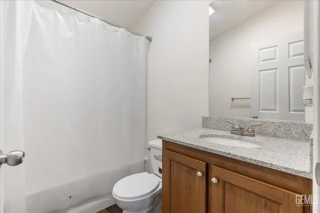 a bathroom with a granite countertop toilet sink and mirror