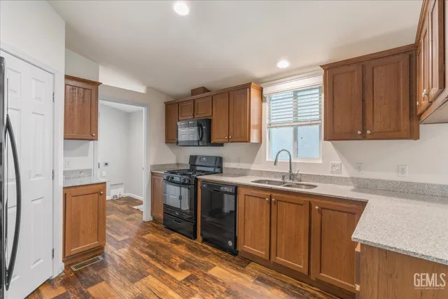 a kitchen with stainless steel appliances granite countertop a sink stove refrigerator and cabinets