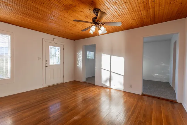 a view of an empty room with window and wooden floor