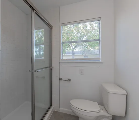 a white toilet sitting next to a window in a bathroom