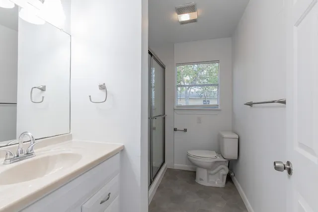 a bathroom with a granite countertop toilet a sink and a mirror