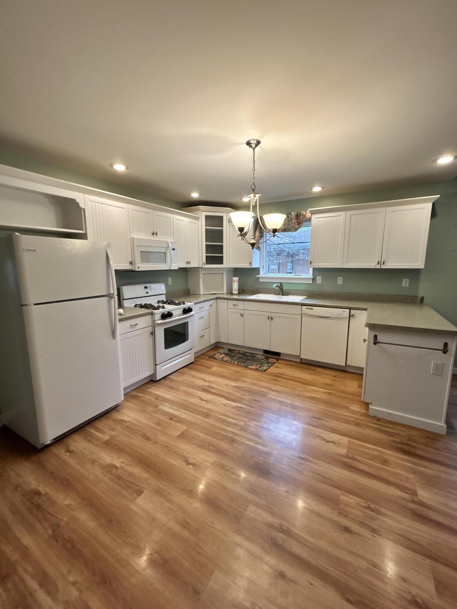 708 South Main Street Kouts, IN 46347 - Photo 5 of 22 a large kitchen with kitchen island a stove a sink dishwasher a refrigerator and white cabinets with wooden floor
