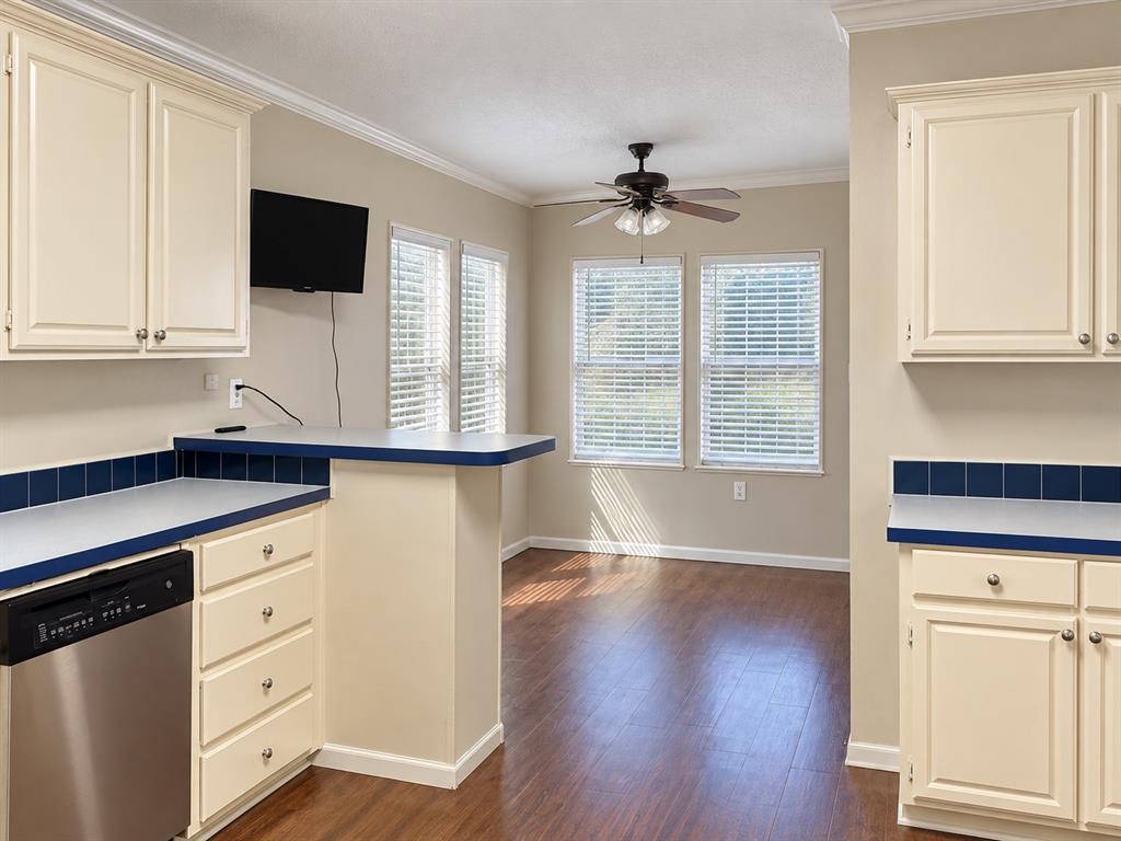 301 South Coppell Road, Unit 51 Coppell, TX 75019 - Photo 4 of 20 Kitchen featuring cream-painted cabinetry, blue tile backsplash, stainless steel dishwasher, and a breakfast bar
