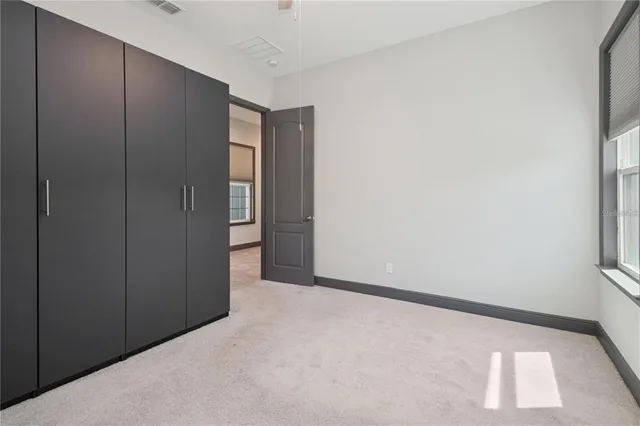an empty room with windows and ceiling fan