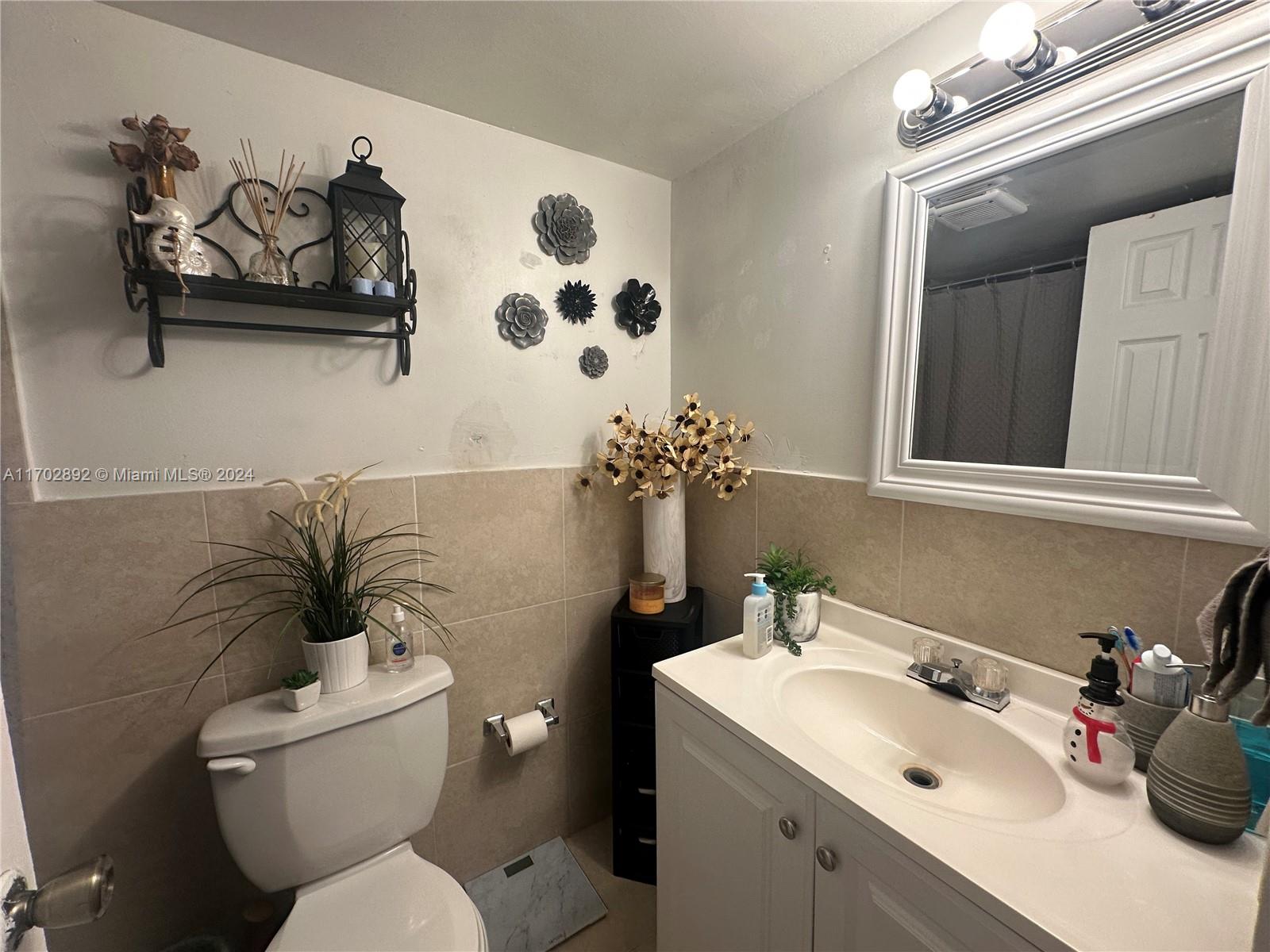 1800 Sans Souci Boulevard, Unit 239 North Miami, FL 33181 - Photo 10 of 15 a bathroom with a toilet sink and mirror