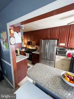 a kitchen with stainless steel appliances granite countertop a refrigerator stove and wooden cabinets