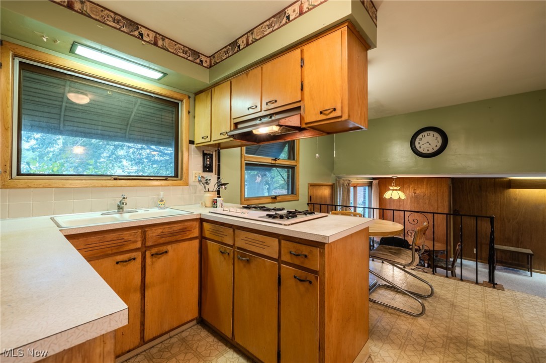 1950 Rush Road Wickliffe, OH 44092 - Photo 35 of 50 Kitchen with a peninsula, brown cabinets, light countertops, light floors, and under cabinet range hood