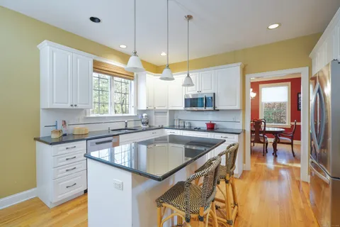 a kitchen with stainless steel appliances granite countertop a sink a stove and a wooden floors