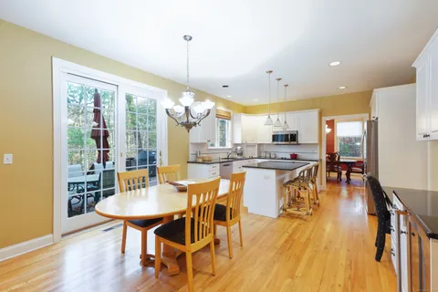 a view of a dining room and livingroom with furniture wooden floor a chandelier