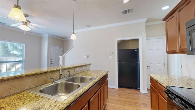 a kitchen with a sink a faucet a refrigerator and wooden floor