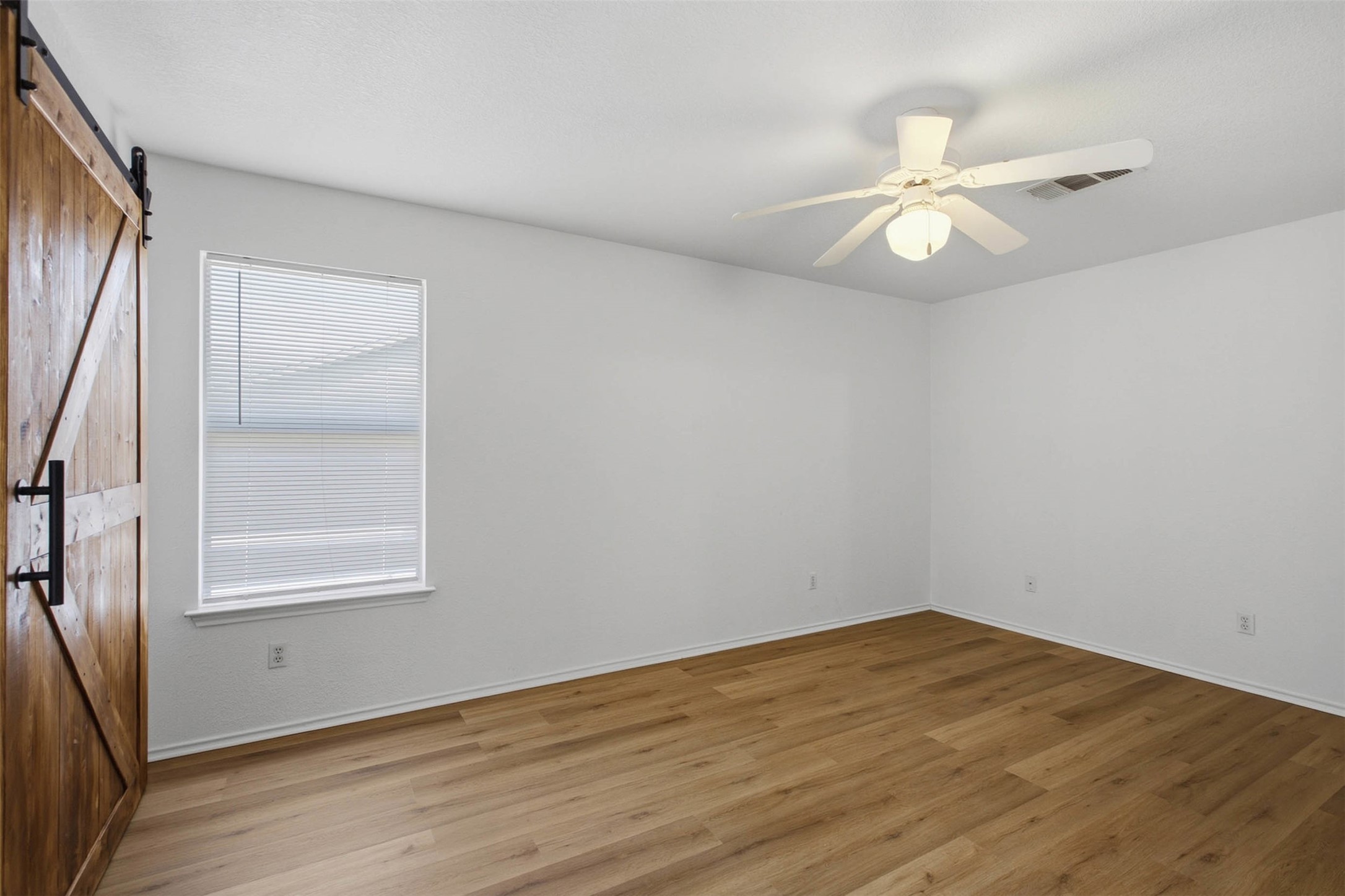 13808 Harris Ridge Boulevard, Unit B Pflugerville, TX 78660 - Photo 21 of 33 Rich wood-look flooring and a rustic sliding door anchor this serene, windowed space.