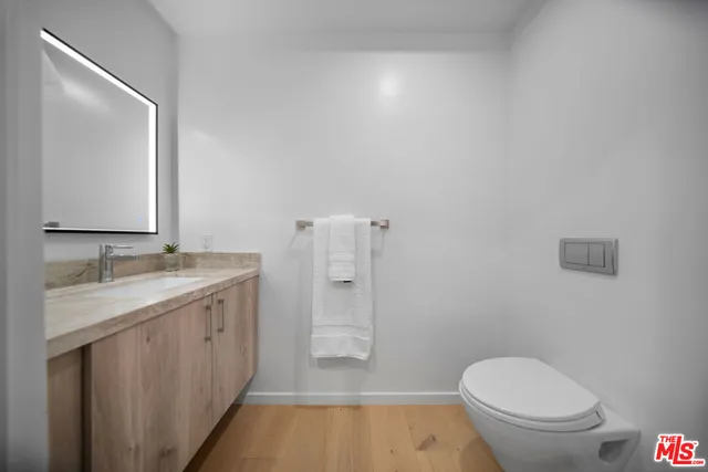 a bathroom with a granite countertop toilet a sink and a mirror