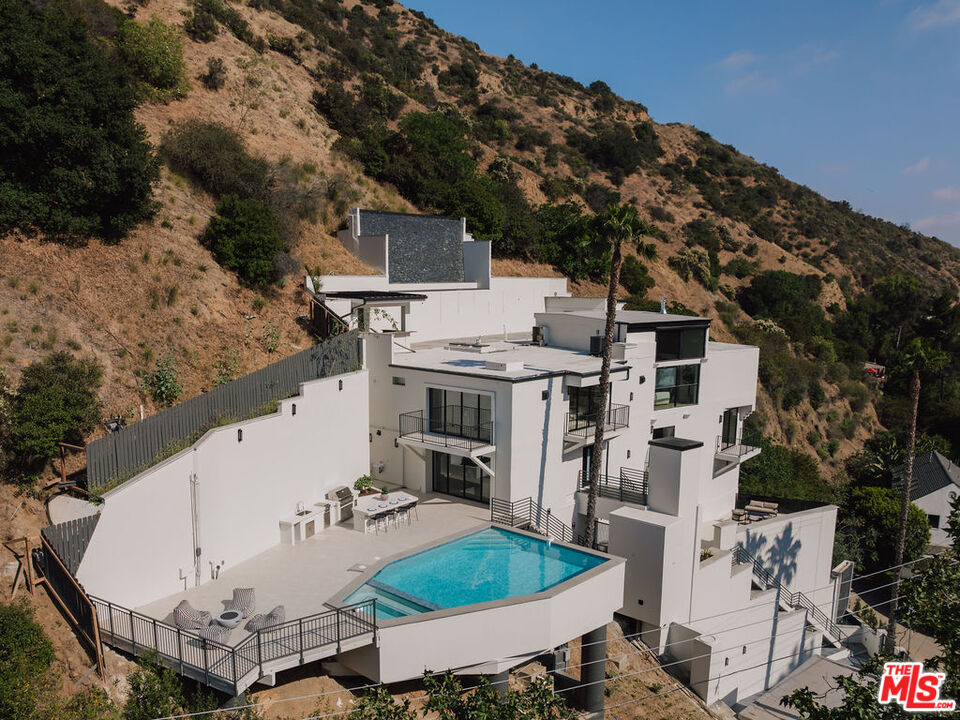 2256 Nichols Canyon Road Los Angeles, CA 90046 - Photo 36 of 45 a view of a white house with a chairs and table in a patio