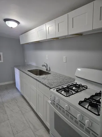 a kitchen with granite countertop a sink stove and cabinets