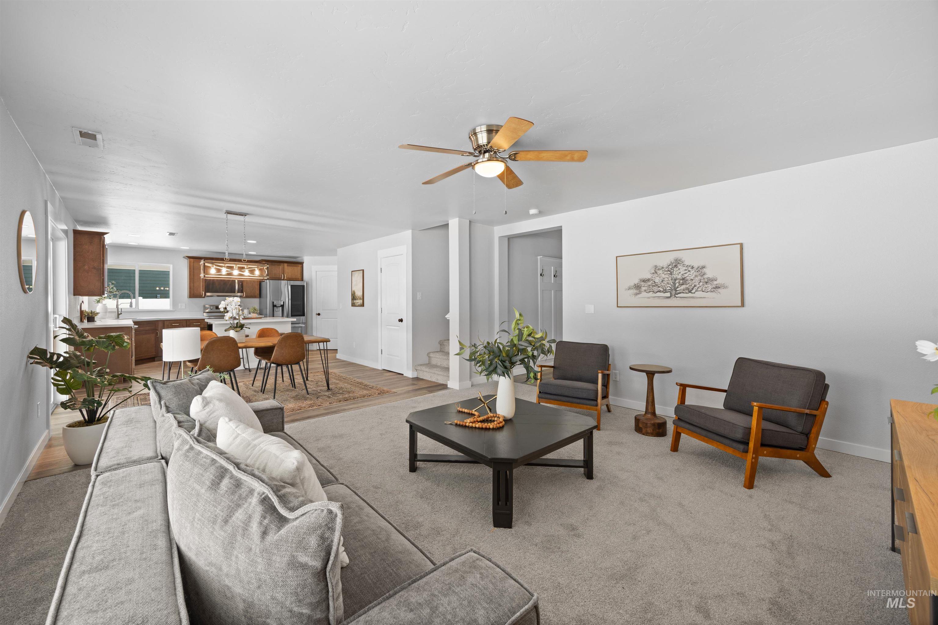 300 South Rocker Avenue Kuna, ID 83634 - Photo 9 of 49 Open-concept living area featuring neutral carpeting, a ceiling fan with wood blades, and abundant natural light