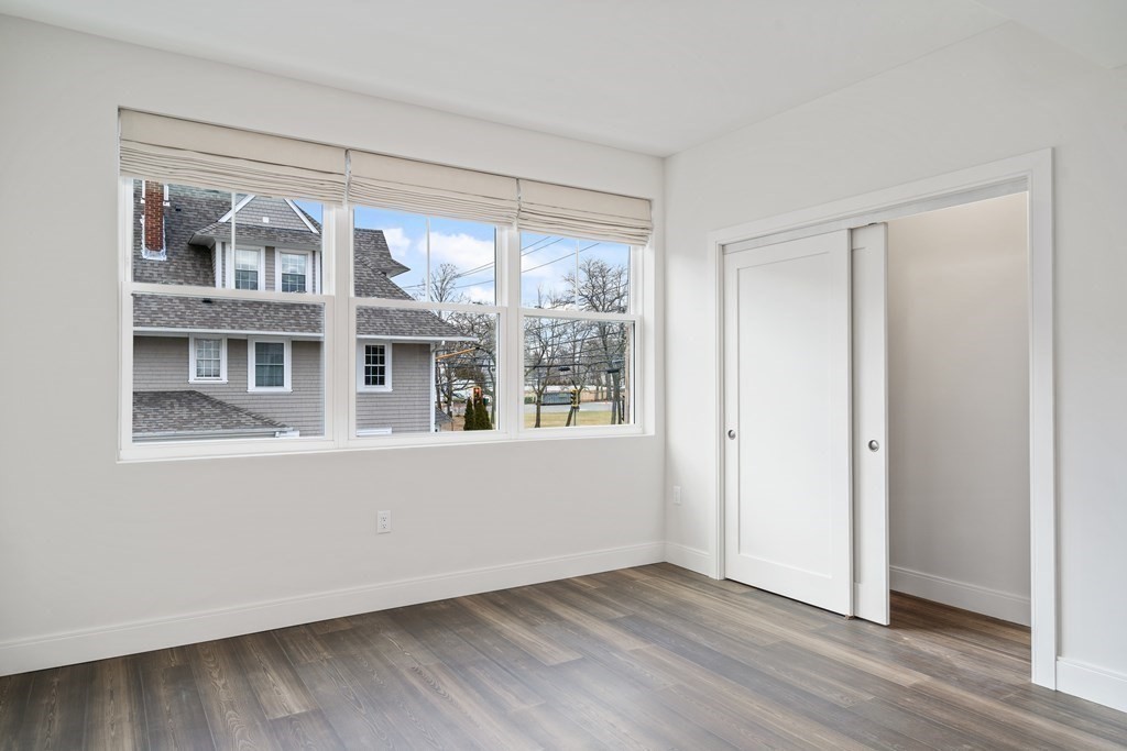 429 Cherry Street, Unit 12 Newton, MA 02465 - Photo 13 of 20 a view of an empty room with wooden floor and windows
