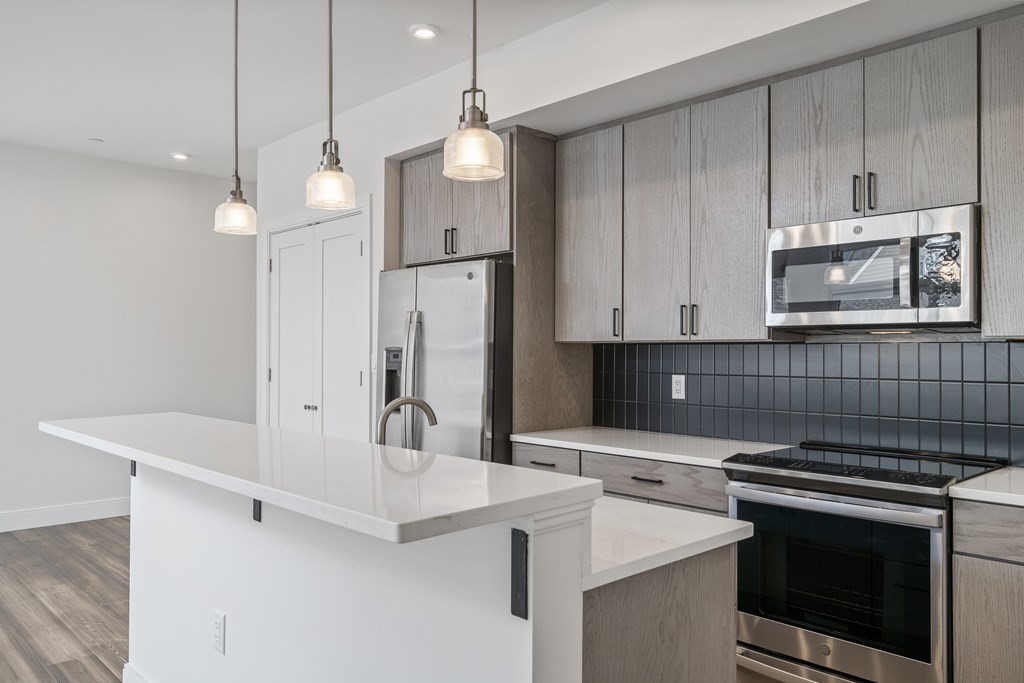 429 Cherry Street, Unit 12 Newton, MA 02465 - Photo 7 of 20 a kitchen with kitchen island a stove a sink and a refrigerator with wooden floor