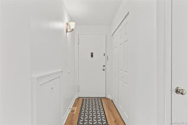 a view of a hallway with wooden floor and a bathroom