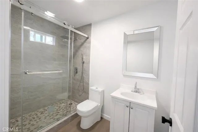 a bathroom with a shower sink vanity mirror and toilet