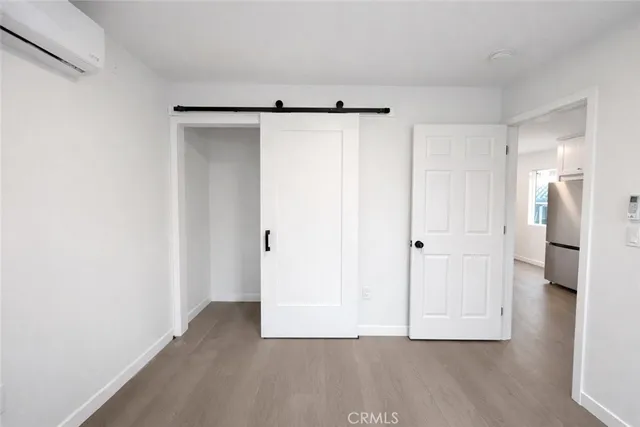 a view of an empty room with wooden floor and a bathroom