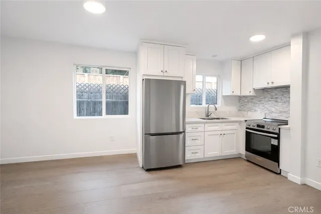 a kitchen with granite countertop a refrigerator stove top oven and sink