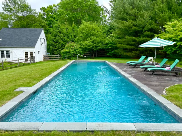 a view of swimming pool with lawn chairs under an umbrella