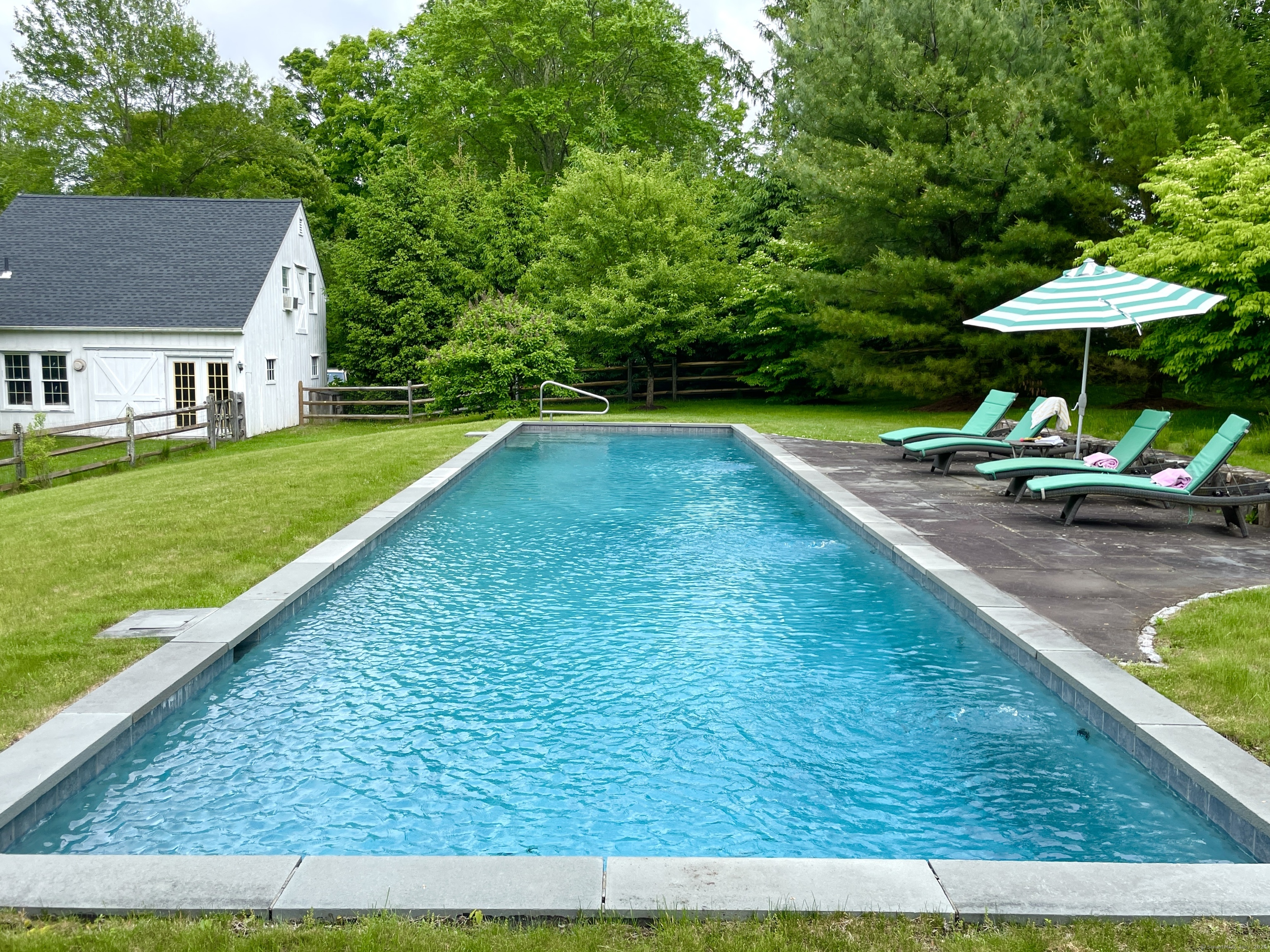 a view of swimming pool with lawn chairs under an umbrella