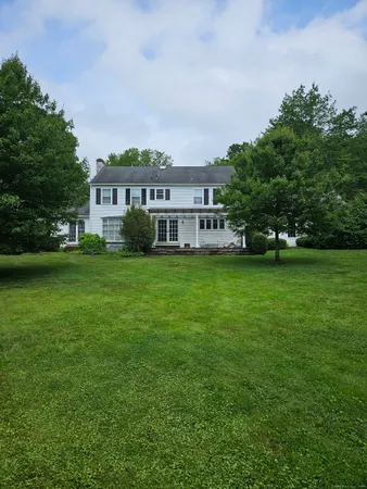 a view of a house with a big yard and large trees