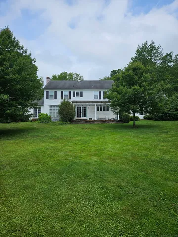 a view of a house with a big yard and large trees