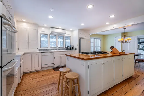 a large kitchen with white cabinets and wooden floor