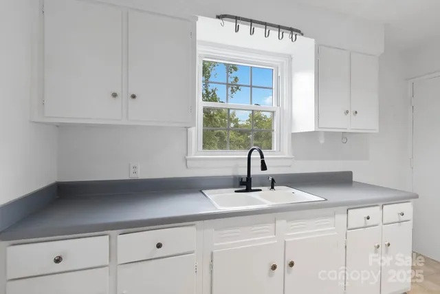 a kitchen with granite countertop white cabinets and window