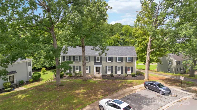 a view of a big house with a big yard plants and large trees