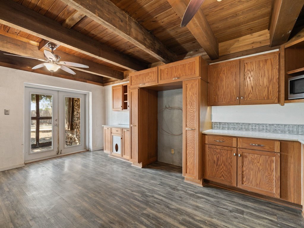 20416 Wilson Road Coupland, TX 78615 - Photo 19 of 39 Exposed wood ceiling beams and durable plank flooring define this rustic kitchen space.