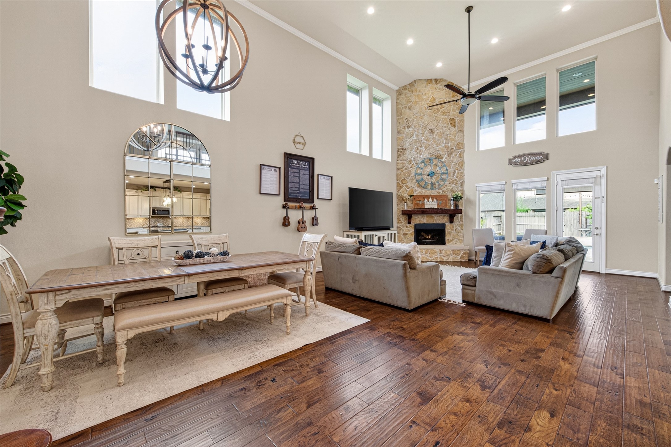 25611 Ellis Ridge Court Katy, TX 77494 - Photo 48 of 49 This spacious living area features high ceilings, a stone fireplace, and large windows for plenty of natural light. The open floor plan includes a cozy seating area and a charming dining space with elegant furnishings, all set on beautiful hardwood flooring.