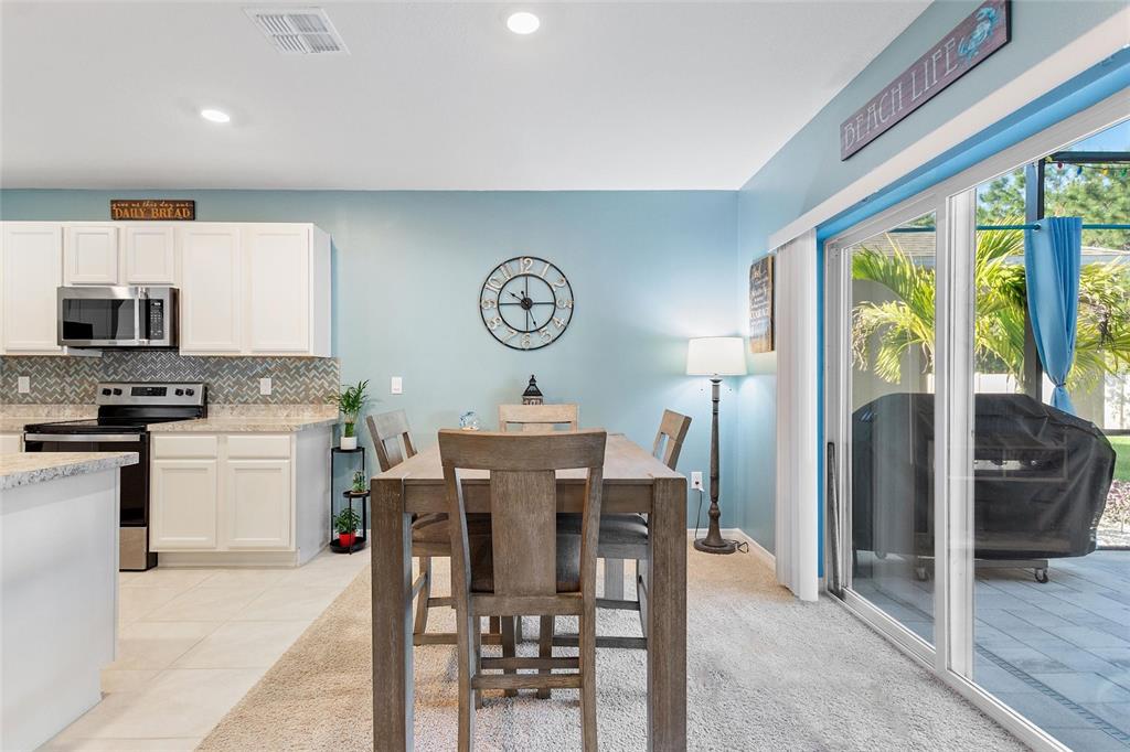 856 Sun Burst Road Winter Haven, FL 33880 - Photo 6 of 54 a kitchen with stainless steel appliances granite countertop a stove top oven a refrigerator a dining table and chairs with wooden floor