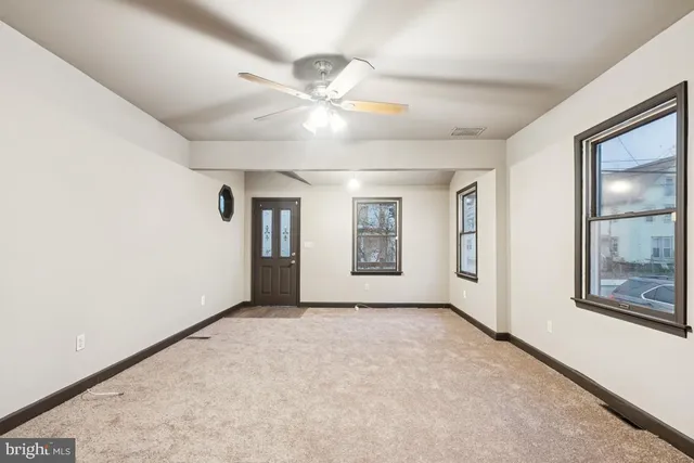 an empty room with windows and fan