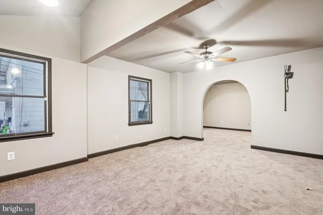 an empty room with windows and ceiling fan