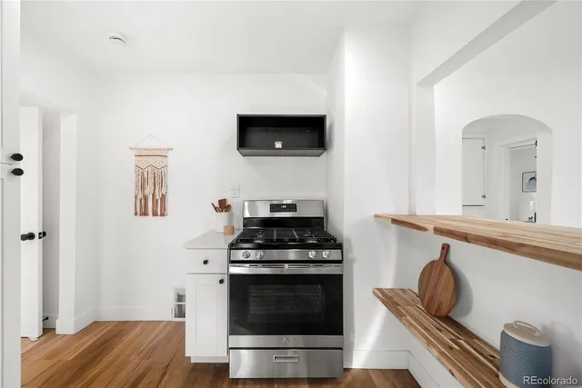 a kitchen with granite countertop a stove and a wooden floor