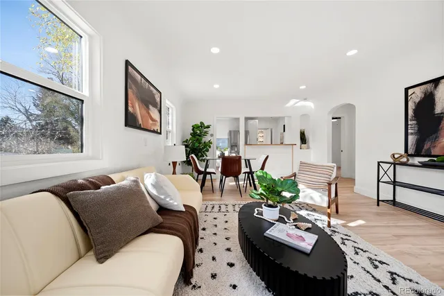 a living room with furniture potted plant and kitchen view