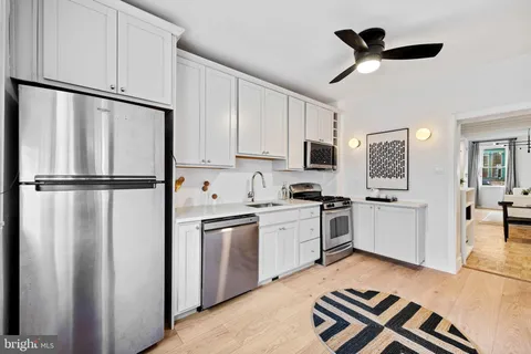 a kitchen with stainless steel appliances granite countertop a refrigerator a sink a stove and white cabinets