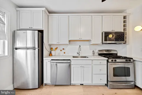a kitchen with white cabinets and stainless steel appliances