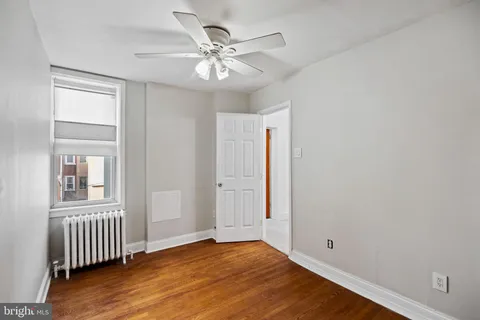 an empty room with wooden floor chandelier fan and windows