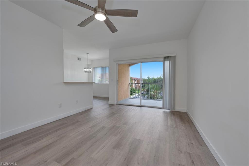 1885 Florida Club Drive, Unit 8305 Naples, FL 34112 - Photo 3 of 22 Unfurnished living room featuring light wood-style flooring, a ceiling fan, and a chandelier