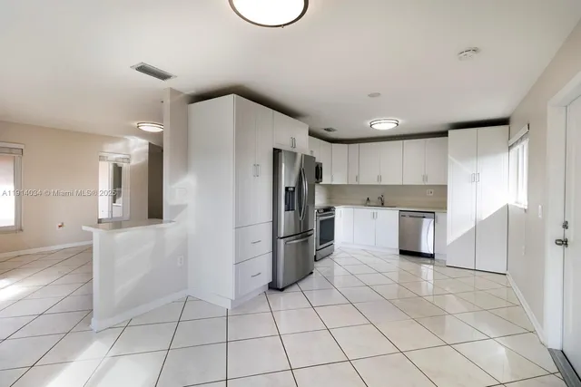 a kitchen with a refrigerator a oven and white cabinets