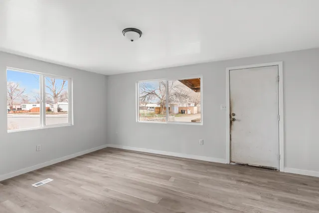 a view of an empty room with wooden floor and a window