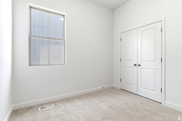7243 West Terraine Road West Jordan, UT 84081 - Photo 20 of 31 Bright interior space featuring a double-hung window, light-colored carpet, white baseboards, and a double-door closet with spherical hardware