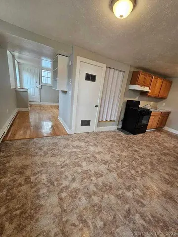 a view of a livingroom with wooden floor and kitchen space