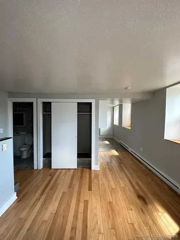 a view of an empty room with window and wooden floor