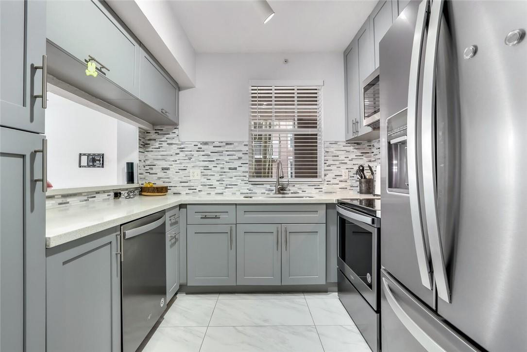 6882 West Sample Road, Unit 6882 Pompano Beach, FL 33063 - Photo 6 of 26 a kitchen with stainless steel appliances granite countertop a sink stove and refrigerator